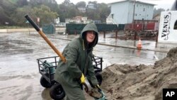 Resident Laurie Morse, 59, shovels wet sand into bags in the pouring rain, a last ditch effort to keep a rising creek out of her garage in the town of Rio Del Mar in Aptos, Calif., Jan. 11, 2023. 