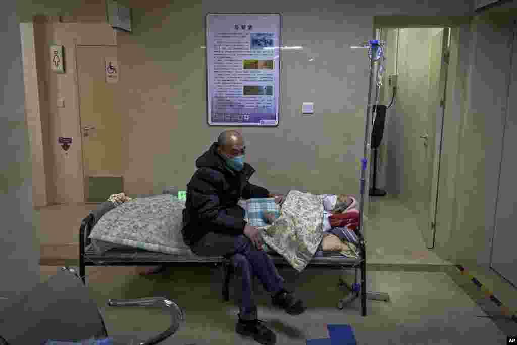 Човек кој носи маска за лице седи до својот постар роднина во салата на одделот за итни случаи во болница во Пекинг, Кина. Додека ковид-19 продолжува да ја пробива Кина, светските организации и влади ја повикаа земјата да почне да споделува податоци.