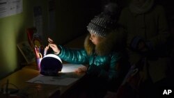Alexandra, 11, draws at a school building, a "Point of Invincibility," a government-built help station that allows to charge phones with help of generators, serves food, drinks and the possibility to warm up, in Kramatorsk, Ukraine, Dec. 5, 2022.