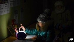 Як сотні тисяч дітей в Україні, що залишилися без тепла і світла, Олександра, якій 11 років, замість школи приходить у «Пункті незламності», де можна зігрітися, зарядити телефони за допомогою генераторів, та поїсти. Краматорськ, Україна, 5 грудня 2022 року.