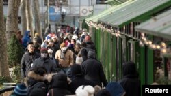 Para pengunjung mengenakan masker saat berkunjung di Bryant Park Winter Village saat malam Natal di Manhattan, New York, AS, 24 Desember 2022. (Foto: Jenah Moon/Reuters)