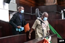Mohamed Cisse, right, and Hassan Barry leave the courtroom, in Abidjan, Dec. 28, 2022.