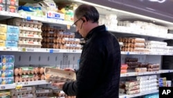 A shopper checks eggs before he purchases at a grocery store in Glenview, Ill., Jan. 10, 2023.