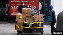 FILE: A delivery person pushes a cart full of Amazon boxes in the Manhattan borough of New York City, New York. Taken Nov. 26, 2021.