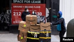 FILE:A delivery person pushes a cart full of Amazon boxes during holiday sales in the Manhattan borough of New York City, New York, U.S., November 26, 2021.