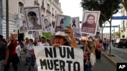 With a sign that reads in Spanish "Not one more death," demonstrators march against Peruvian President Dina Boluarte in Lima, Peru, Jan. 12, 2023.