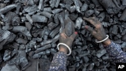 FILE - A woman works at a coal depot in Ahmedabad, India, May 2, 2022.