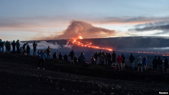 People gather to observe the eruption of the Mauna Loa volcano in Hawaii, Dec. 1, 2022.