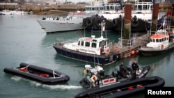 FILE: Members of Britain's Border Force tow into the Port of Dover an inflatable boat used by migrants who were rescued while crossing the English Channel, in Dover, UK. Taken April 14, 2022. 