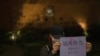 Una manifestante sostiene un cartel con los mensajes "Fuerzas extranjeras no, fuerzas internas" y "El abuso del poder del gobierno hunde a la gente en la miseria y el sufrimiento" durante un encuentro en la Universidad de Hong Kong, el martes 29 de noviembre de 2022. 