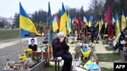 An elderly woman grieves next to the grave of a Ukrainian soldier during Ukraine&#39;s Army Day at Lychakiv Cemetery in the western city of Lviv.