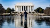 A man and a boy walk across the frozen Reflecting Pool towards the Lincoln Memorial on the National Mall in Washington, DC, Dec. 26, 2022. 