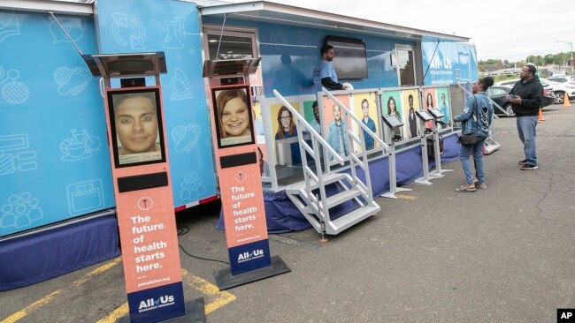 FILE - People stand by the All of Us Mobile Education and Enrollment Center at the Community Health Center on State Street in Meriden, Conn., May 13, 2019. (Dave Zajac/Record-Journal via AP, file)