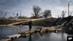 A man crosses the river on the debris of a damaged bridge in Bakhmut, the site of the heaviest battles with the Russian troops, in the Donetsk region, Dec. 11, 2022. 