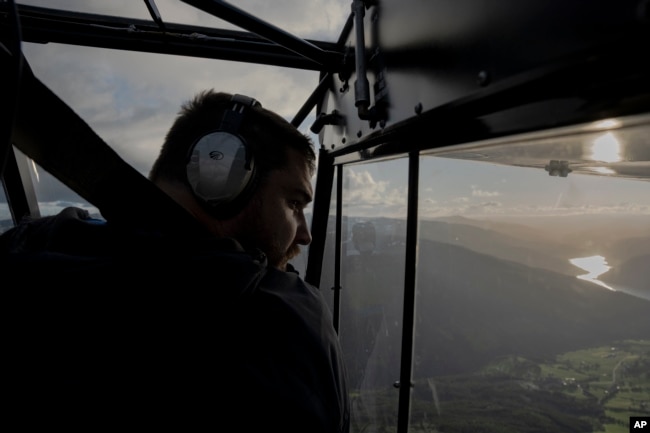 Garrett Fisher, an American aviator and adventurer, looks out the window of his plane while on a mission to photograph glaciers in Norway, on July 29, 2022. (AP Photo/Bram Janssen)