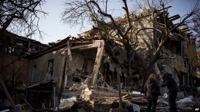 基辅居民谢尔盖·卡哈利茨基(Serhii Kaharlytskyi，右)2023年1月2日站在他被俄军空袭摧毁的住宅外。他的妻子艾琳娜(Iryna)2022年12月31日死于那次空袭。(美联社照片)