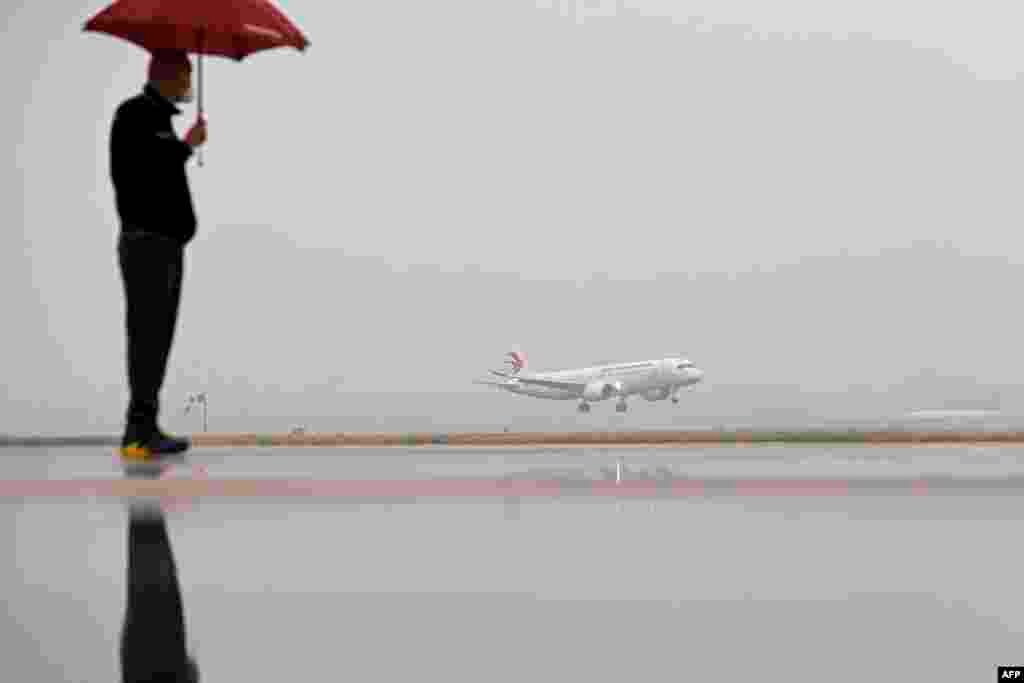 A man watches a Commercial Aircraft Corp of China (COMAC) C919 aircraft, China's first domestically produced large passenger jet, landing at Hongqiao International Airport after it is formally handed over to China Eastern Airlines in Shanghai.