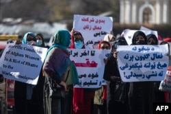 FILE - Women hold placards during a protest calling for their rights to be recognized, near the Shah-e-Do Shamshira mosque in Kabul, Nov. 24, 2022.