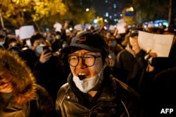 FILE - Protesters march along a street during a rally for the victims of a deadly fire as well as a protest against China's harsh Covid-19 restrictions in Beijing on November 28, 2022. (Photo by Noel CELIS / AFP