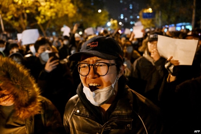 FILE - Protesters march along a street during a rally for the victims of a deadly fire as well as a protest against China's harsh Covid-19 restrictions in Beijing on November 28, 2022. (Photo by Noel CELIS / AFP