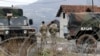 FILE - U.S. soldiers serving in the NATO-led peacekeeping force KFOR guard a checkpoint on a road near the northern Kosovo border crossing of Jarinje, along the Kosovo-Serbia border, Dec. 18, 2022.