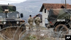 FILE - U.S. soldiers serving in the NATO-led peacekeeping force KFOR guard a checkpoint on a road near the northern Kosovo border crossing of Jarinje, along the Kosovo-Serbia border, Dec. 18, 2022.