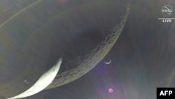 In this handout video grab courtesy of NASA TV the Earth is visible as a crescent in the minutes after Orion finished its engine burn around the moon on Dec. 5, 2022. (Photo by Handout / NASA TV / AFP)