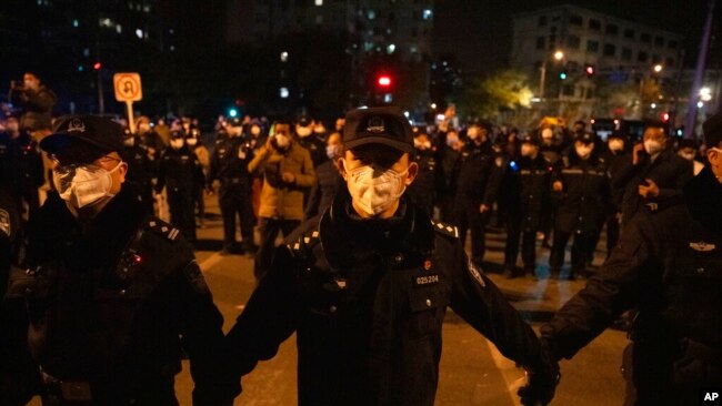 Chinese policemen form a line to block off protesters in Beijing, Nov. 27, 2022.