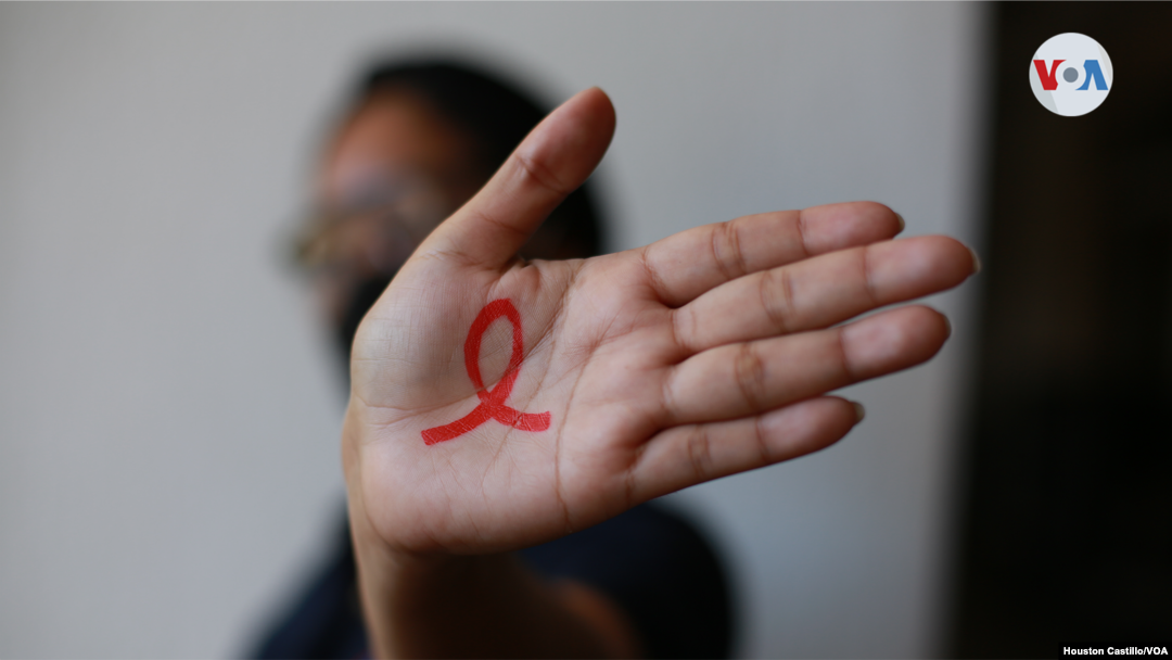 Una persona portadora de VIH muestra un lazo rojo en su mano, un símbolo internacional ideado para mostrar apoyo a la lucha contra el SIDA y solidaridad con las víctimas de la enfermedad.