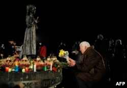 A local resident lays flowers during a ceremony at a monument of the victims of the Holodomor, Ukrainian for "death by starvation," in Kyiv, Nov. 26, 2022. The country marked the 90th anniversary of the famine killed millions of Ukrainians under Stalin.