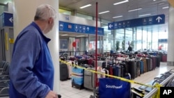 A traveler looks at luggage in the baggage claim area inside the Southwest Airlines terminal at St. Louis Lambert International Airport, in St. Louis, Missouri, Dec. 28, 2022.