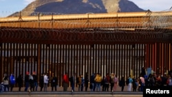 Migrantes hacen cola cerca de la valla fronteriza, después de cruzar el río Bravo, para solicitar asilo en El Paso, Texas, visto desde Ciudad Juárez, México, el 5 de enero de 2023.