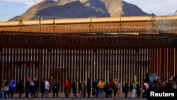 Migrants queue near the border fence, after crossing the Rio Bravo river, to request asylum in El Paso, Texas, as seen from Ciudad Juarez, Mexico, Jan. 5, 2023. 