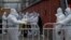 Workers in protective suits stand guard at a barricade as others prepare for their duties in a locked-down neighborhood as part of COVID-19 controls in Beijing, Nov. 24, 2022.
