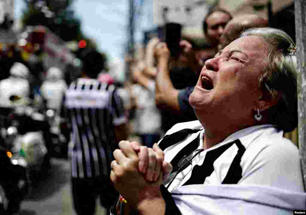 A mourner reacts as the casket of Brazilian soccer legend Pele is transported to the Santos&#39; Memorial Cemetery during his funeral procession in Santos.