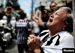 Mourners react as the coffin of Brazilian football legend Pele is brought to the Santos Memorial Cemetery during a funeral procession in Santos on January 3, 2023.  (REUTERS/Ueslei Marcelino)