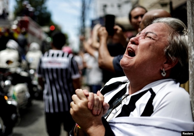 A mourner reacts as the casket of Brazilian soccer legend Pele is transported to the to the Santos' Memorial Cemetery during his funeral procession in Santos, Jan. 3, 2023. (REUTERS/Ueslei Marcelino)