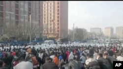 In this photo provided Nov 23, 2022, protesters face off against security personnel in white protective clothing at the factory compound operated by Foxconn Technology Group who runs the world's biggest Apple iPhone factory in Zhengzhou in central China's Henan province.