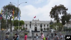 Orang-orang berjalan melewati gedung Kongres selama kunjungan delegasi OAS di Lima, Peru, Senin, 21 November 2022. (AP/Guadalupe Pardo)