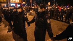 Chinese policemen form a line to stop protesters marching in Beijing, Nov. 27, 2022. 