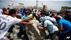 Supporters of ousted Peruvian President Pedro Castillo roll a boulder onto the Pan-American North Highway during a protest against his detention, in Chao, Peru, Dec. 15, 2022.