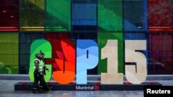 Police officers walk past a sign as they patrol outside the Palais de Congres, during the opening of COP15, a two-week U.N. biodiversity summit in Montreal, Canada, Dec. 6, 2022.