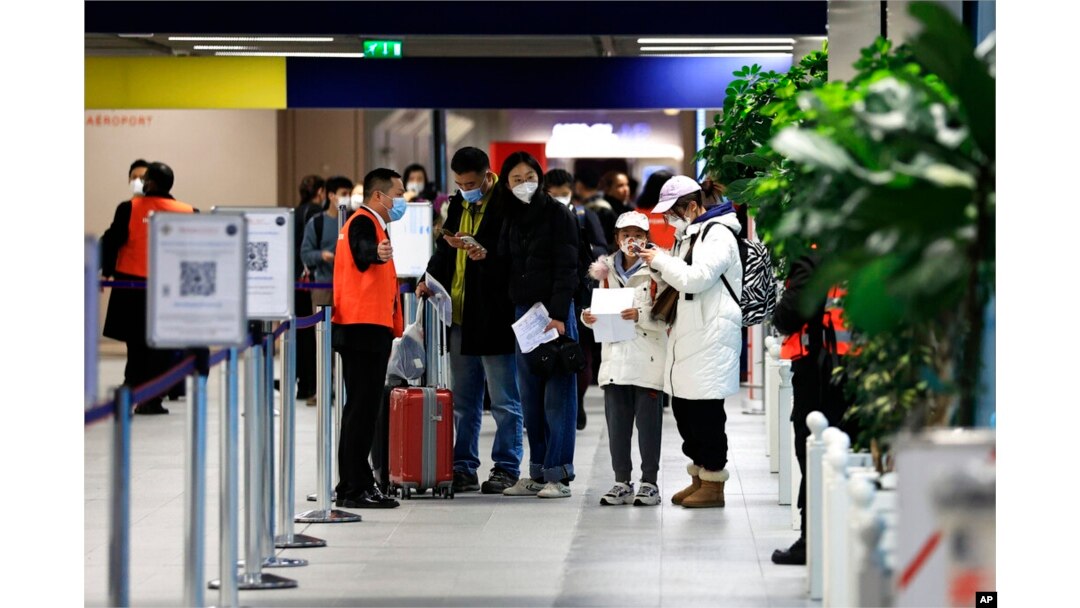 Penumpang yang datang dari China menunggu di depan area tes COVID-19 yang ditetapkan di bandara Roissy Charles de Gaulle, utara Paris, Minggu, 1 Januari 2023. ( AP/Aurelien Morissard)