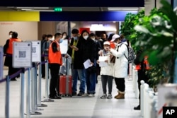 Penumpang yang datang dari China menunggu di depan area tes COVID-19 yang ditetapkan di bandara Roissy Charles de Gaulle, utara Paris, Minggu, 1 Januari 2023. ( AP/Aurelien Morissard)