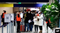 Penumpang yang datang dari China menunggu di depan area tes COVID-19 yang ditetapkan di bandara Roissy Charles de Gaulle, utara Paris, Minggu, 1 Januari 2023. (AP/Aurelien Morissard)