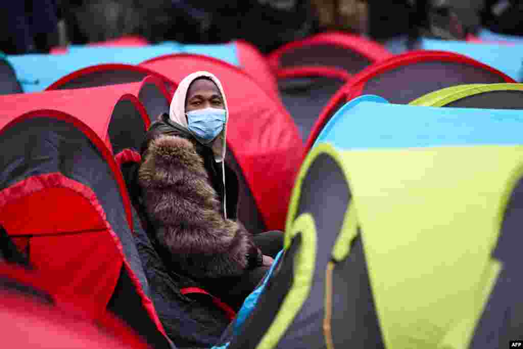 An unaccompanied juvenile migrant sits in a tent in front of the Council of State during an event to demand the sheltering of unaccompanied minors who are homeless, in Paris.