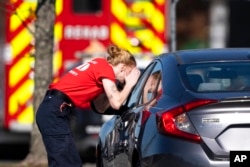 A first responder checks a parked car at the scene of a mass shooting at a Walmart, Nov. 23, 2022, in Chesapeake, Va.