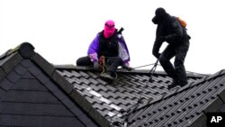 Masked climate activists climb on a roof top at the village Luetzerath, near Erkelenz, Germany, Jan. 12, 2023. 