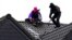 Masked climate activists climb on a roof top at the village Luetzerath, near Erkelenz, Germany, Jan. 12, 2023. 