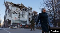 A woman walks past an office building damaged by shelling in Donetsk, Russian-controlled Ukraine, Dec. 15, 2022. 